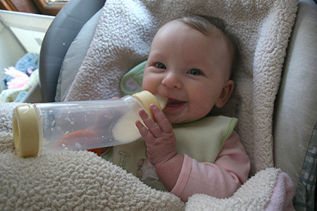 Baby in baby seat with bottle.